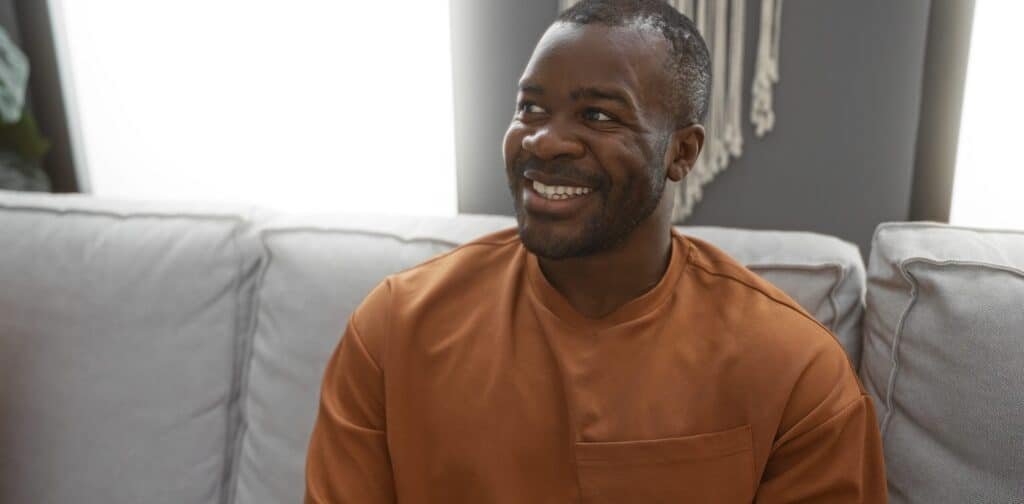 Handsome,Man,Smiling,In,A,Cozy,Living,Room,,Showcasing,A